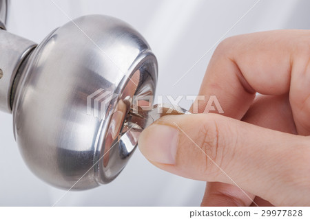 Hand use the key for unlocking door knob on door 29977828