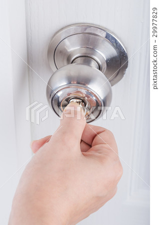 Hand use the key for unlocking door knob on door 29977829