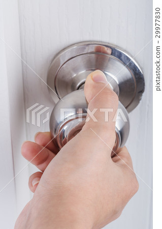 Hand opening door knob on white door 29977830