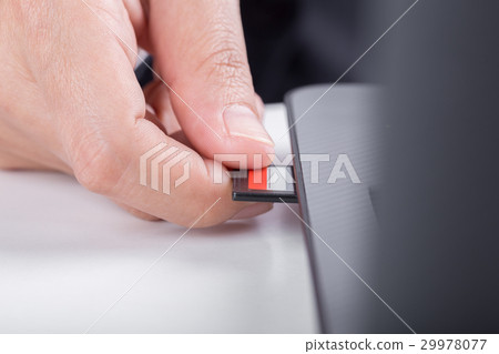 hand inserting SD card into laptop 29978077