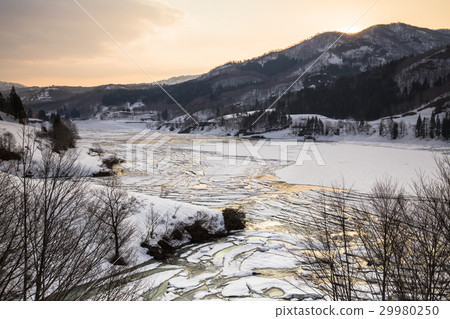 A calm morning glow and reflection of the Nabe river dam lake where the snow and ice on the lake surface of Niigata prefecture broke 29980250