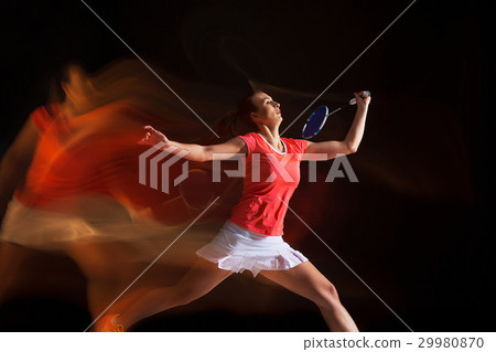 Young woman playing badminton over black 29980870
