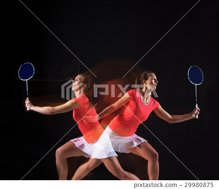 Young woman playing badminton over black 29980875