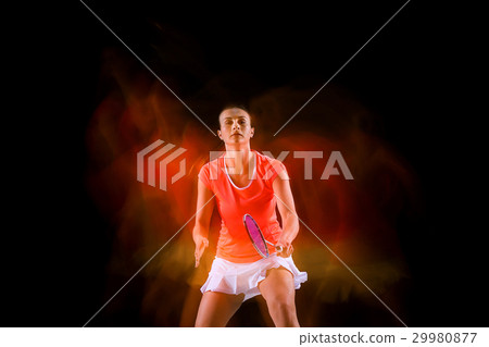 Young woman playing badminton over black Young woman playing badminton over black 29980877