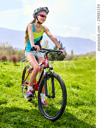 Woman traveling bicycle on green grass in summer 29982154