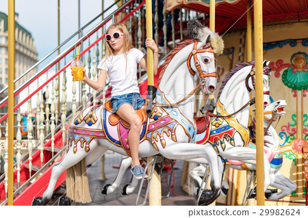 Girl riding on a merry go round. Little girl 29982624