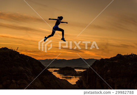 Woman jump through the gap between hill 29982788
