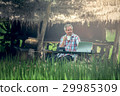 Old man sitting at a desk on a outdoor 29985309