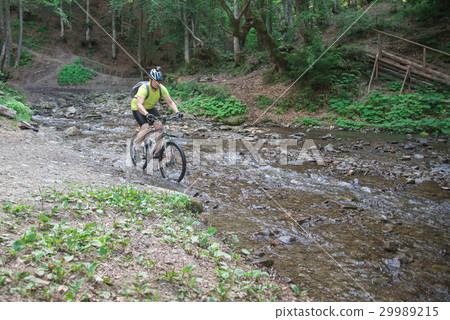 Young athlete crossing water barrier with bicycle 29989215