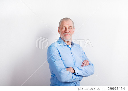 Senior man in light blue shirt smiling, studio 29995434