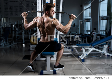 man exercising at the gym on a machine man exercising at the gym on a machine 29997324