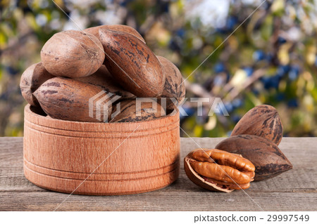 pecan nuts in a wooden bowl on the old board with 29997549