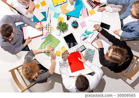 Team sitting behind desk, checking reports 30009565