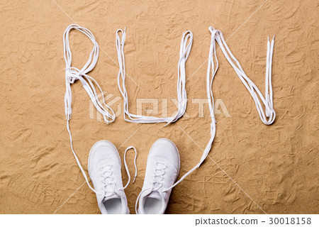 Running shoes and run sign made of shoelaces, sand 30018158