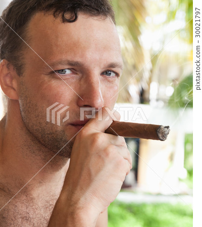 Young European man smokes big cigar, close up Young European man smokes big cigar, close up 30021797