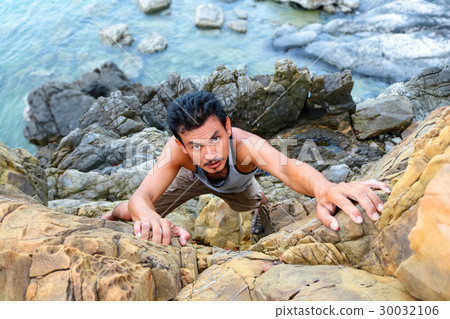 Asian man climbing the rocks near the sea. Asian man climbing the rocks near the sea. 30032106