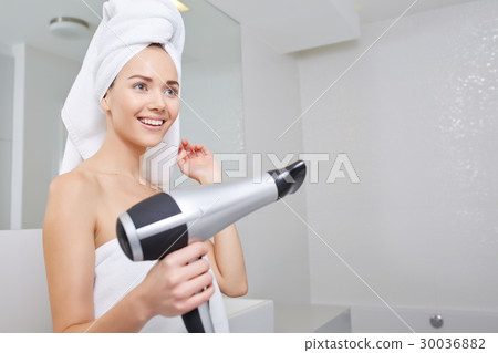Young woman blow drying hair in bathroom 30036882