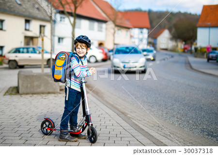 Little kid boy in helmet riding with his scooter 30037318