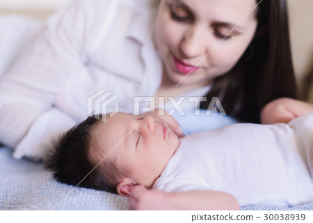 Happy young mother near sleeping baby Happy young mother near sleeping baby 30038939