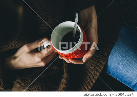 Red Knitted woolen cup  in female hands. 30043184