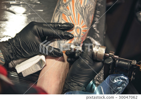 Master drawing tattoo on arm of man 30047062