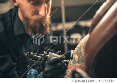 Serious male doing picture on arm 30047118