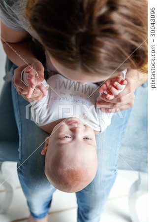 Newborn child lies on his mother's lap 30048096