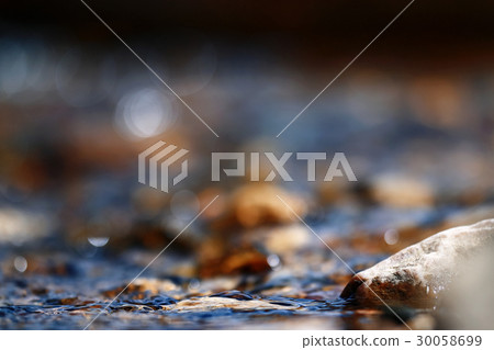 Multi-colored pebbles in a stream Multi-colored pebbles in a stream 30058699