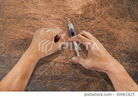 hand using syringe on a wood board hand using syringe on a wood board 30061825