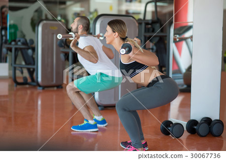 young man and woman with barbell flexing muscles young man and woman with barbell flexing muscles 30067736