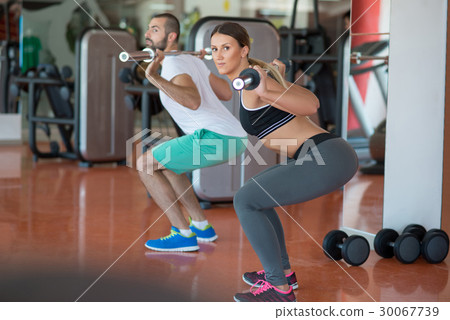 young man and woman with barbell flexing muscles 30067739