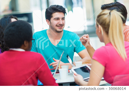 A group of teenagers sitting at the table in cafe A group of teenagers sitting at the table in cafe 30068014