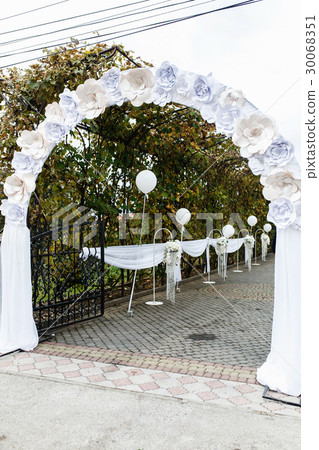 Arch decorated with paper flowers leads 30068351