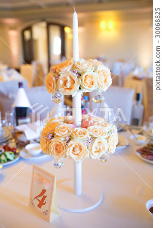 Beige roses decorate white candleholder standing Beige roses decorate white candleholder standing 30068825