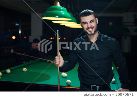 Young smiling man playing billiard game 30070671