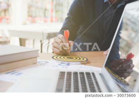 Businessman holding dart hitting business target Businessman holding dart hitting business target 30073600