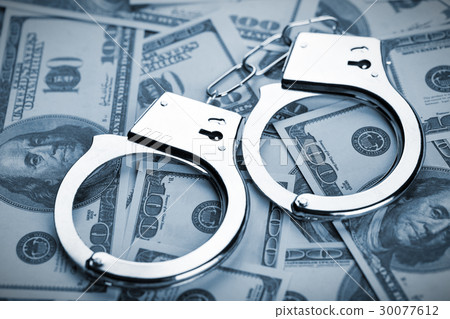 Pair of handcuffs closeup on dollar banknotes 30077612