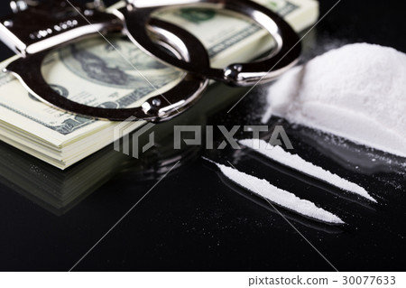 Handcuffs on stack of dollar banknotes and cocaine Handcuffs on stack of dollar banknotes and cocaine 30077633