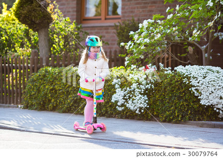 Child riding schooter on way to school 30079764