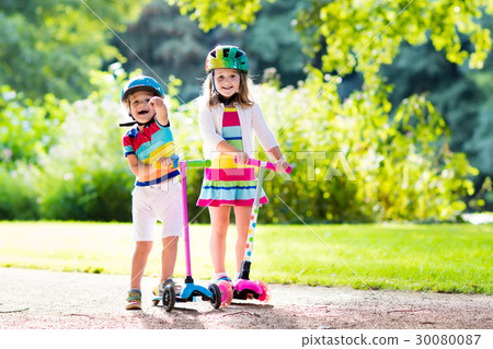 Kids riding scooter in summer park. 30080087