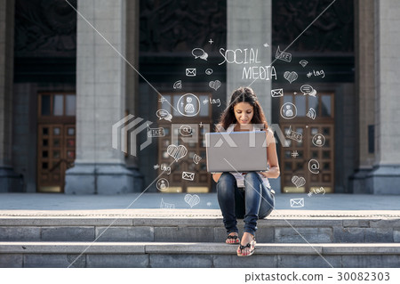 Young woman with laptop sitting on the stairs Young woman with laptop sitting on the stairs 30082303