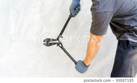 Man wear a glove and holding cutting pliers on gray background. 30087185
