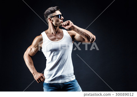 Handsome muscular man in dark glasses and a white Handsome muscular man in dark glasses and a white 30089012