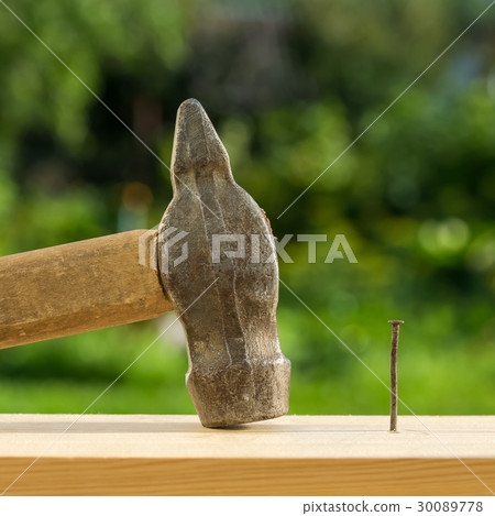 Hammer and nail on wooden plank Hammer and nail on wooden plank 30089778