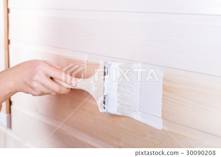 Woman painting wooden boards in white color 30090208