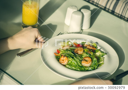 Salad of shrimp in a plate and cutlery in hands 30092979