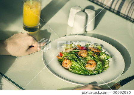 Salad of shrimp in a plate and cutlery in hands 30092980