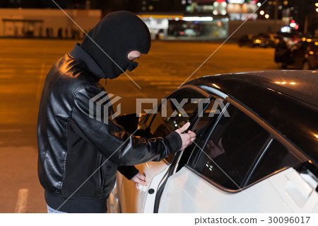 Male thief with balaclava on head opening car door Male thief with balaclava on head opening car door 30096017