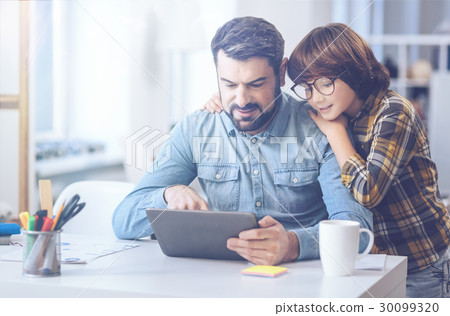 Content boy putting arms around his father 30099320