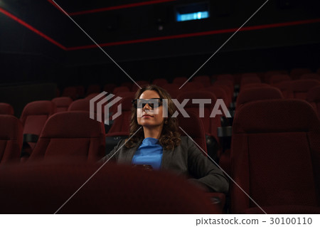 Young woman watches movie 3D at the cinema and drinks coffee, lo 30100110